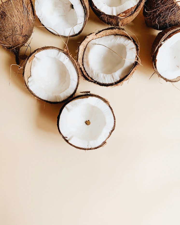 Fresh coconut halves on a cream background